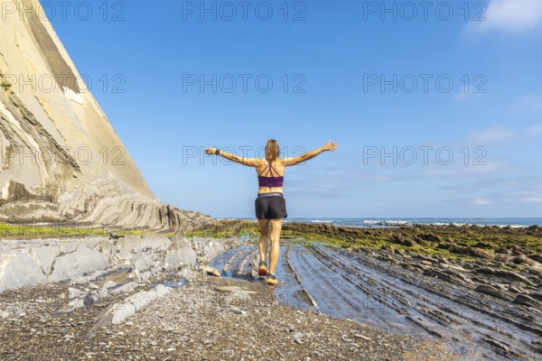 Female athlete enjoying freedom and nature, walking on the unique rock formations of sakoneta beach