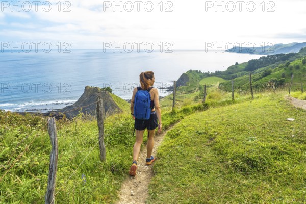 Female hiker enjoying the stunning view of sakoneta beach and its coastal flysch in zumaia, basque