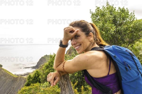 Female hiker with backpack taking a break and enjoying the breathtaking view of sakoneta beach and