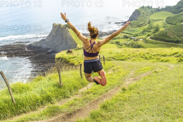 Sportswoman celebrates achieving a fitness goal by leaping in the air with arms outstretched,