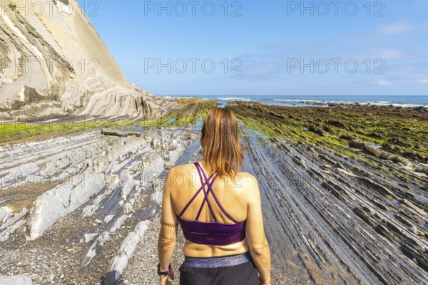 Female tourist exploring the unique geological formations of the flysch cliffs on sakoneta beach in
