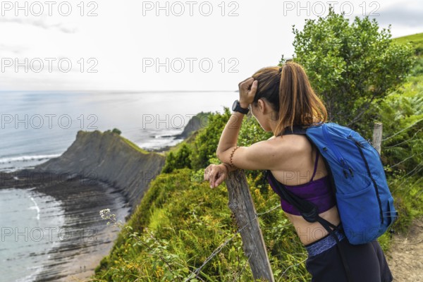 Female hiker enjoying the scenic view of the sakoneta beach and its coastal flysch in zumaia,