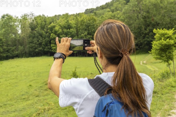 Female hiker taking pictures of the landscape with her smartphone in sakoneta beach area and its