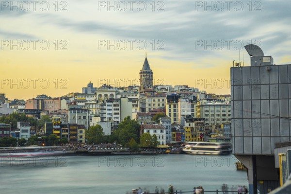 Galata tower rising above colorful buildings along the golden horn in istanbul, turkey, during a