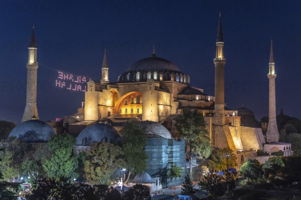 Hagia sophia illuminated at night with a drone light show displaying a religious message in the sky