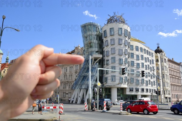 Hand pointing at the famous dancing house in prague, czech republic, a deconstructivist office