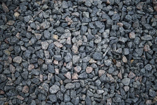 A close-up view of dark gravel featuring small, irregularly shaped stones in shades of gray and