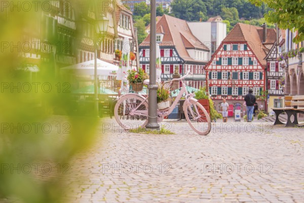 Pink bicycle with flowers in the foreground of a picturesque half-timbered old town with cobbled