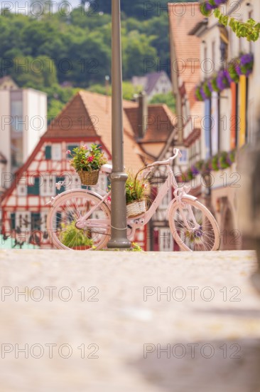 Pink bicycle leaning against a street lamp in a charming old town with red half-timbered houses,