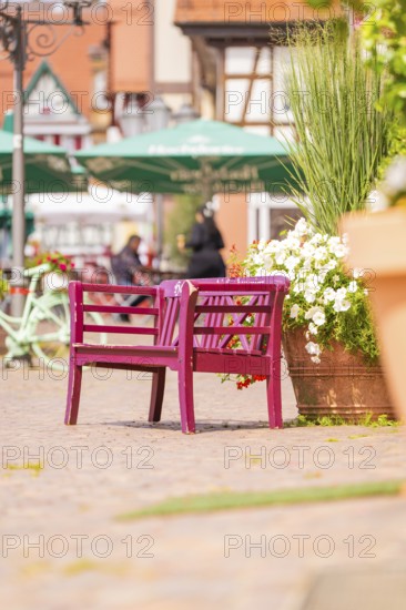 Pink bench with flowers in lively old town with cafés and summery atmosphere, small town pearl