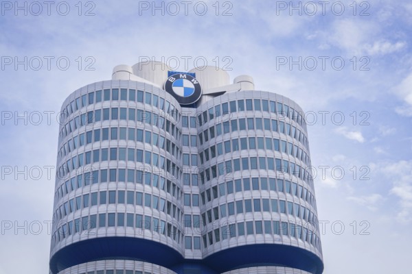 High-rise building with round glass facades and prominent logo against a slightly cloudy sky, BMW