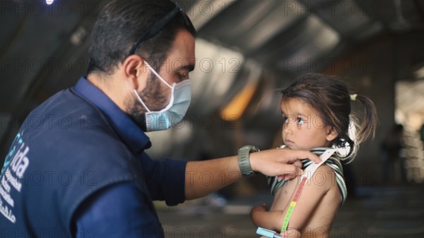 A doctor examines children's malnutrition inside a refugee camp. Malnutrition was measured using a