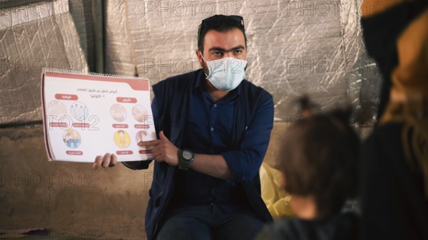 A community health worker giving instructions to refugees on how to deal with the cholera outbreak