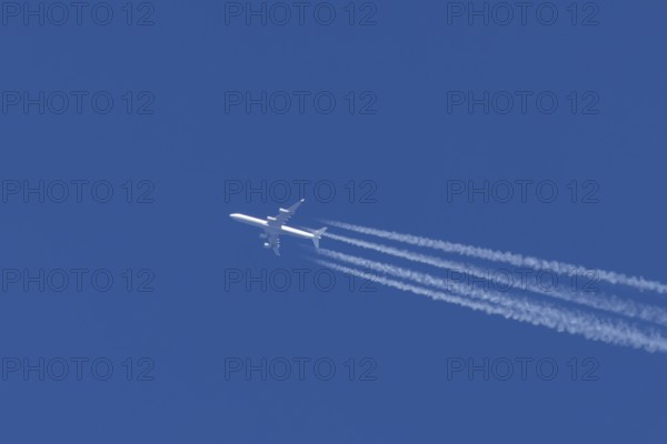 Airbus A340-300 jet aircraft of Lufthansa airlines in flight in a blue sky with vapour trails or
