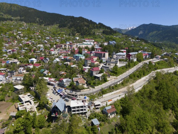 Cityscape embedded in mountains, with colourful houses and lush green surroundings, aerial view,