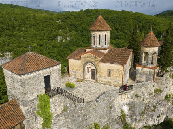 Historic church with tiled roofs on a hill surrounded by dense forest, aerial view, Motsameta