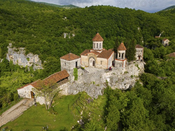 Historic monastery on steep hills surrounded by lush greenery, aerial view, Motsameta Monastery,