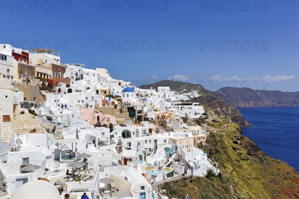 White and colourfully painted holiday homes, orthodox church with blue dome on the edge of the