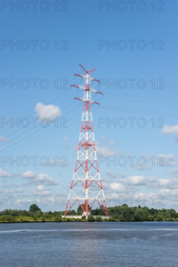 An extremely high electricity electricity electricity pylon, marked white and red, stands on the
