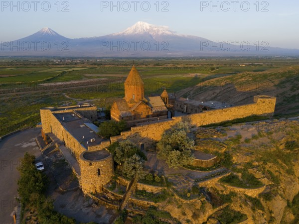 Monastery in the light of the sunrise with mountains in the background and peaceful nature, aerial