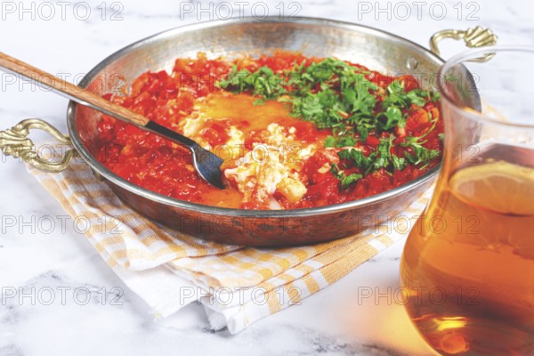 Traditional Turkish dish, scrambled eggs with tomatoes, Menemen, with herbs, in a frying pan,