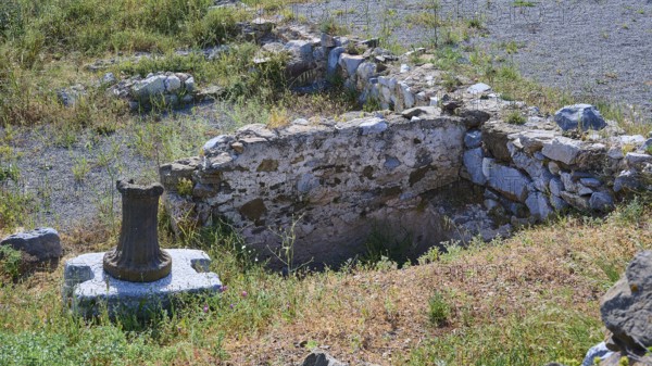 Ancient ruins with preserved column on a stone block in the surroundings of a historical site,