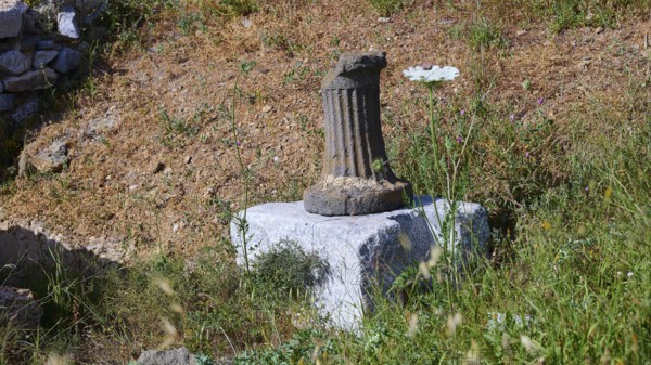 An old column on a pedestal surrounded by grass at a historical site, ancient Roman bath, Tallaras,