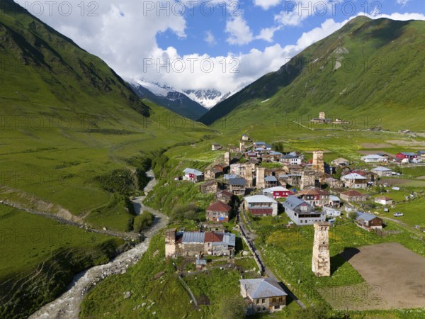 A picturesque village with historic buildings and towers in a green valley between mountains,