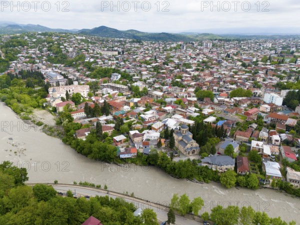 Overview of a hilly cityscape with river, residential buildings and a prominent church, aerial