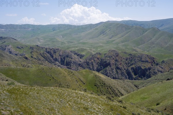 Green hills with clouds in the sky and a gorge depicting a peaceful landscape, view of the