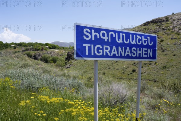 Road sign of Tigranashen in front of a hilly landscape with wild flowers, K?rk, Karki or
