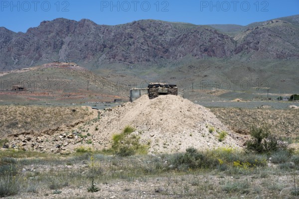 Abandoned-looking bunker on a hill in a mountainous landscape, embrasure on the border to the