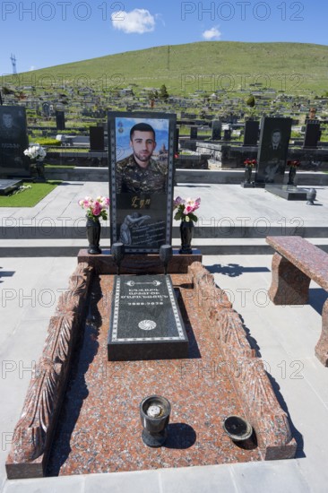 Tomb monument with portrait and flowers, surrounded by green hills and blue sky, Tomb of 2020,