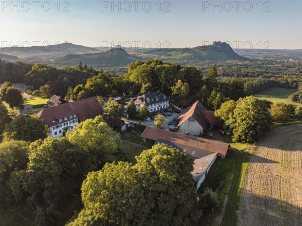 Luftbild von einer Hofsiedlung mit dem Berggasthaus Rosenegg, dahinter die Hegauberge,