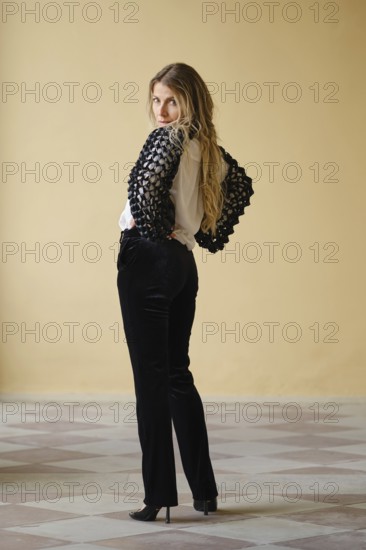 A middle-aged woman stands confidently with her back turned, showcasing a chic black and white