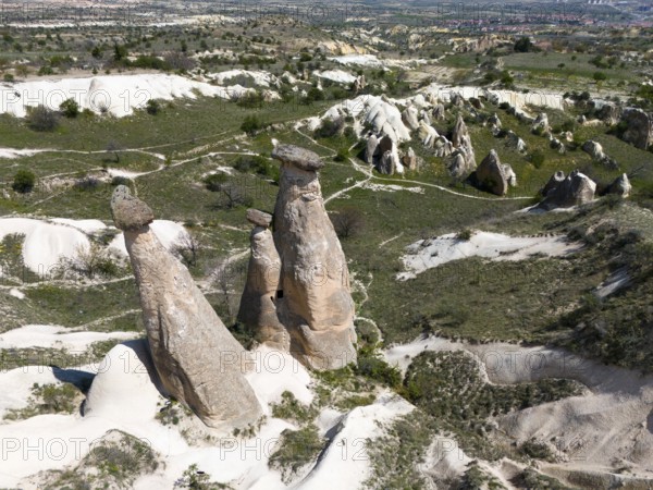 High rock formations in hilly landscape with green areas, aerial view, fairy chimneys near Ürgüp,