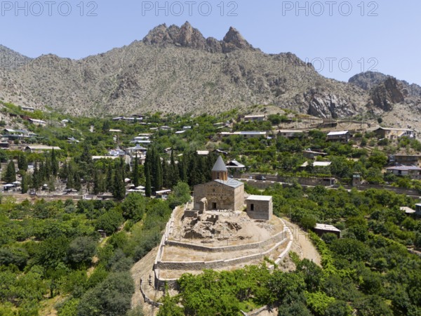 Historic mountain church surrounded by lush vegetation and impressive mountains, aerial view, St