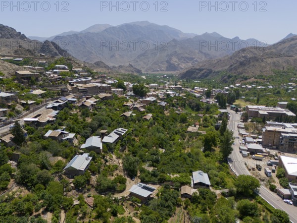 Panoramic view of a village along a road amidst green hills and mountains, aerial view, Meghri,