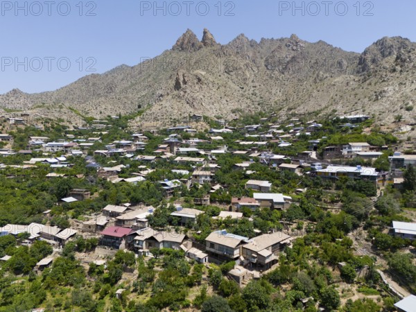 Traditional mountain village with scattered houses and hills surrounded by mountains, aerial view,