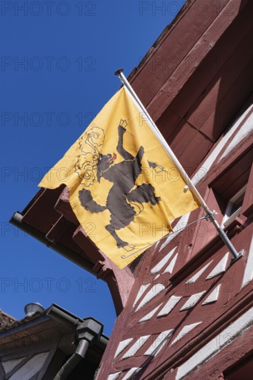 Cantonal flag of Schaffhausen on a half-timbered house, pictogram of a black goat striding freely