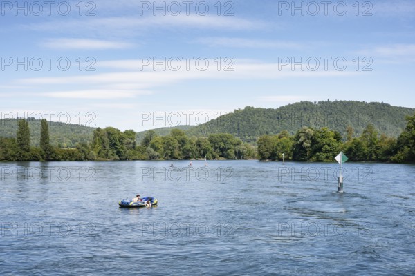Inflatable boat, stand up paddler, swimming next to a fairway on the Rhine, Hochrhein near
