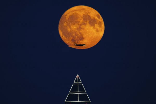 The full moon passes over the top of the Messeturm in Frankfurt am Main, while the silhouette of an