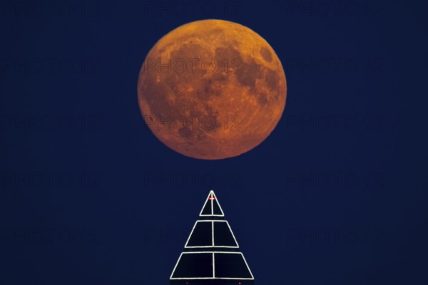 The full moon passes over the top of the Messeturm in Frankfurt am Main, Frankfurt am Main, Hesse,