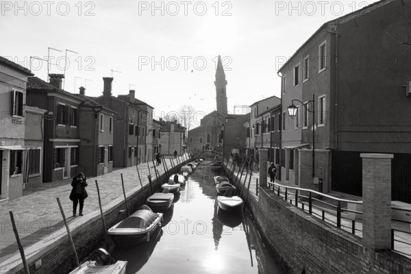 Strollers along the canal, typical street scene in winter, monochrome, facades in Burano, leaning
