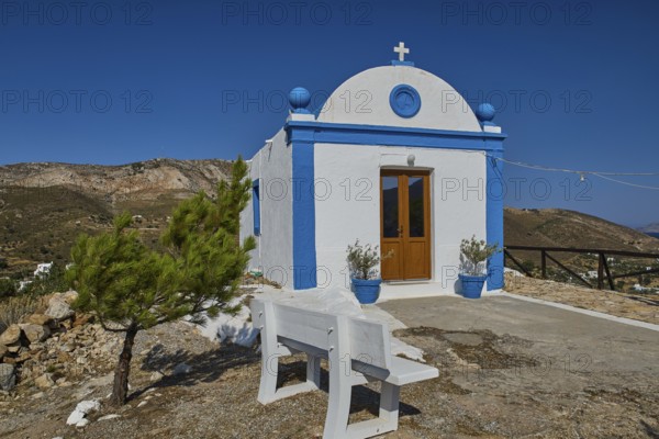 White chapel with blue roof and cross, visible in mountainous, clear surroundings, Panagia tou
