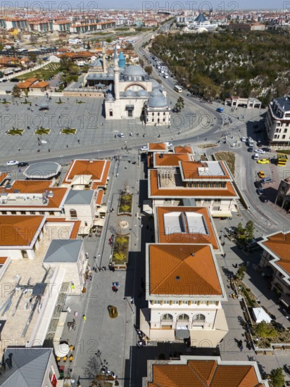 Bird's eye view of an urban landscape with red roofs and a mosque in the background in sunny