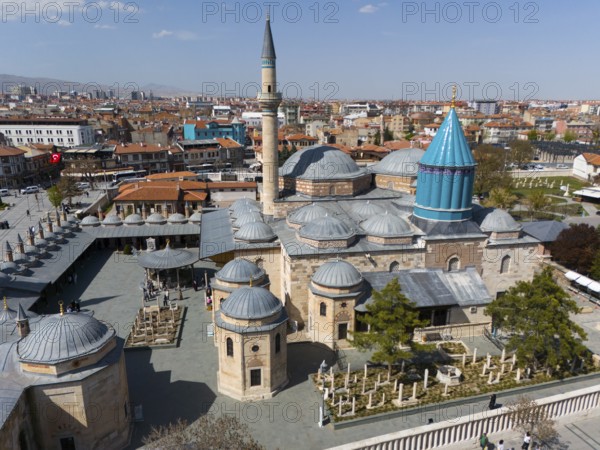 Historic mosque with minaret and domes in the middle of a cityscape under a blue sky, aerial view,