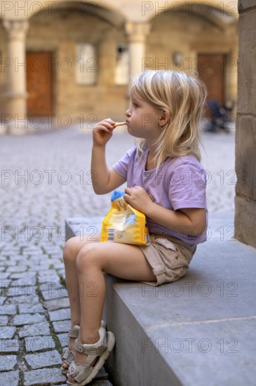 Girl, 4 years, blonde, summery dressed, sitting on step, eating biscuits, summer, Stuttgart,