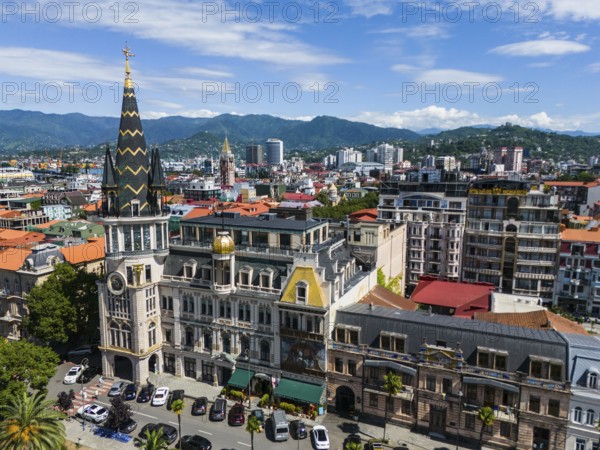 Charming city with historic architecture against a backdrop of mountains and blue sky, aerial view,