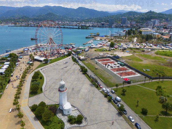 Aerial view of a harbour area with Ferris wheel, lighthouse and town by the sea, surrounded by